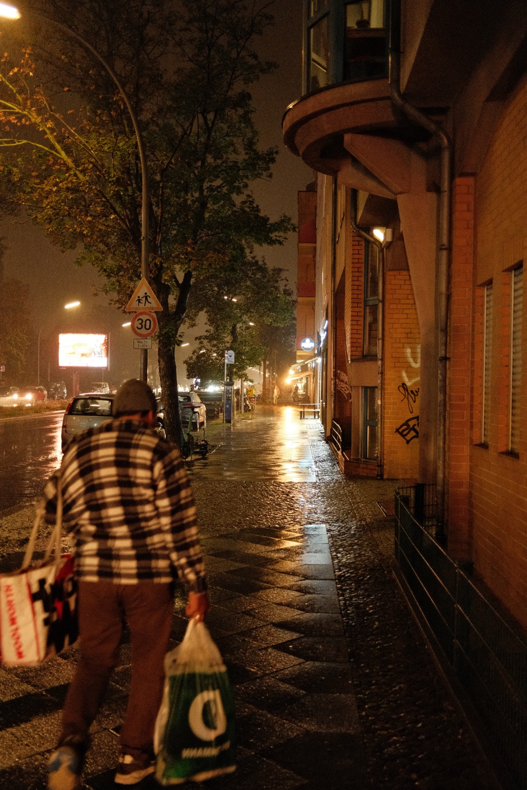 Nasse Straße bei Nacht, ein Mensch von hinten