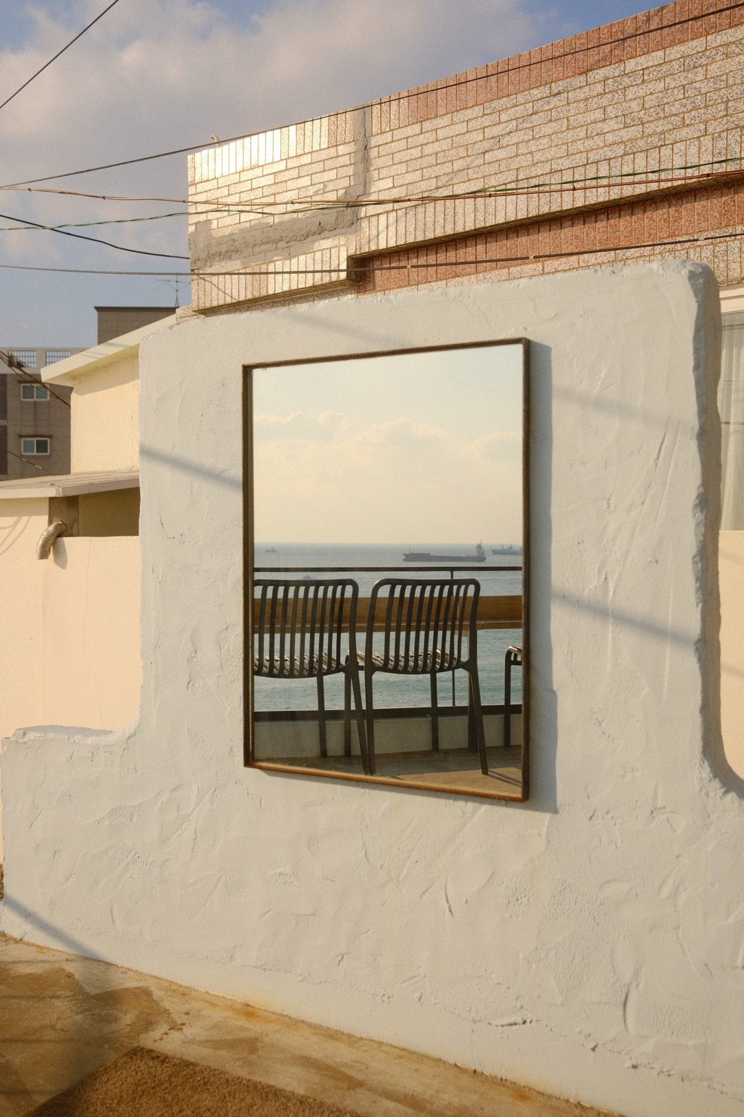 Spiegel an einer weißen Wand, darin das Meer