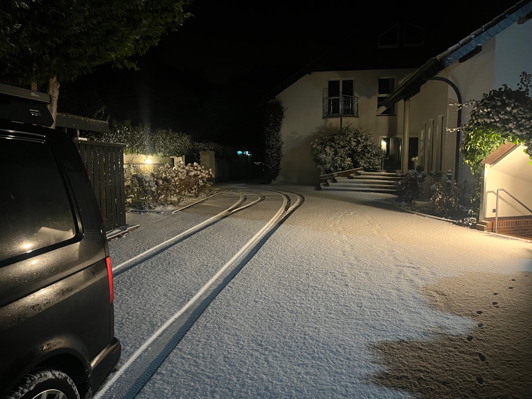 Verschneite Straße nachts mit Reifenspuren
