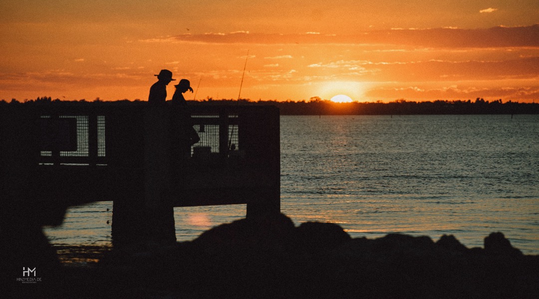 Sonnenuntergang über dem Meer, zwei Silhouetten am Ufer