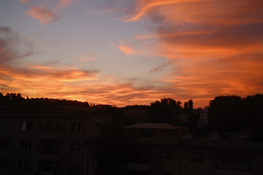 Glühender Abendhimmel über dunklen Dächern